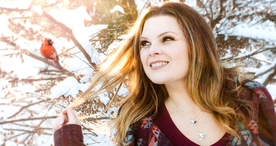 Spirit Medium Tiffany Rice in the snow with a cardinal above her.